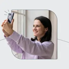 Uśmiechnięta dziewczyna robi sobie selfie telefonem, ćwicząc, jak zrobić zdjęcie do dowodu.