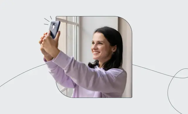 Uśmiechnięta dziewczyna robi sobie selfie telefonem, ćwicząc, jak zrobić zdjęcie do dowodu.